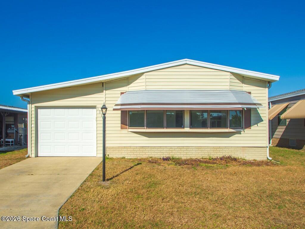 View of front of home with a front lawn, concrete driveway, and an attached garage