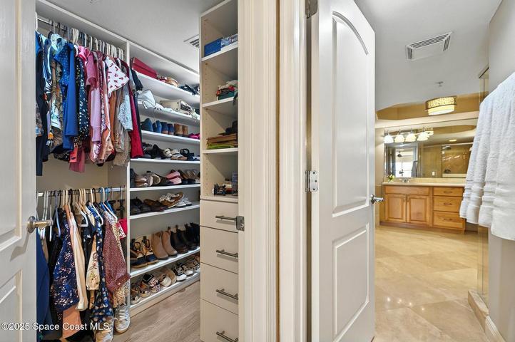 Identical walk in custom closets on opposite sides of the hallway entering the primary bathroom.