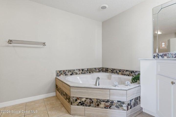 Master Soaking Tub with tile surround and Mosaic Stone & Glass Backsplash
