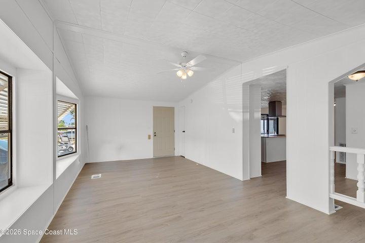 Unfurnished living room with a ceiling fan, light wood-style floors, and lofted ceiling