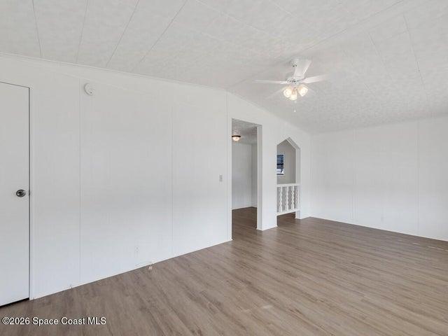 Empty room featuring light wood finished floors, vaulted ceiling, and ceiling fan