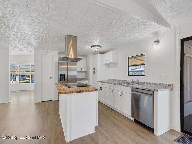 Kitchen featuring butcher block counters, white cabinets, a kitchen island, island range hood, and stainless steel appliances