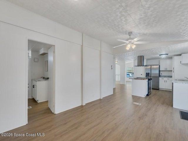 Kitchen featuring a ceiling fan, light wood-style floors, stainless steel fridge with ice dispenser, white cabinetry, and open floor plan