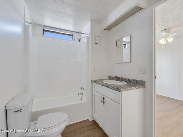 Full bathroom with light wood-style flooring, vanity, bathtub / shower combination, and ceiling fan