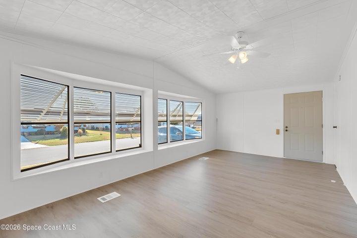 Spare room with a ceiling fan, lofted ceiling, and light wood-type flooring
