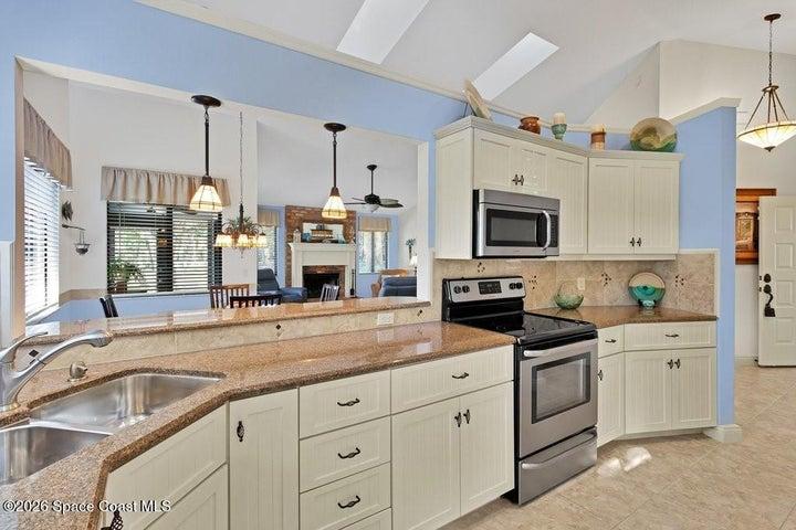 Light filled kitchen with vaulted ceilings and an open layout overlooking the dining & living area. Features include white beadboard cabinetry, stainless steel appliances, granite counter tops and charming "tiffany style" pendant accent lighting....