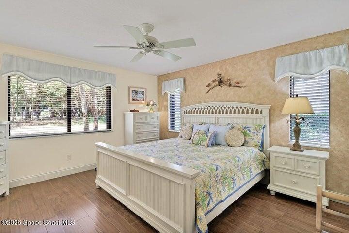 Spacious coastal-style primary suite with Pergo Engineered wood flooring, abundant natural light, and serene views of the landscape and golf course. Custom Painted accent wall - NO Wallpaper!