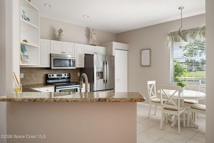 Additional view of kitchen offers view of breakfast nook with large window view of pond