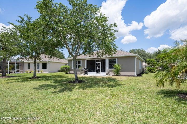 Expansive backyard featuring a lush lawn, established trees, and mature landscaping