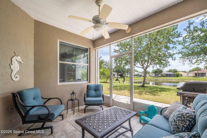 Enclosed porch features tile flooring, ceiling fan and large screened view of pond