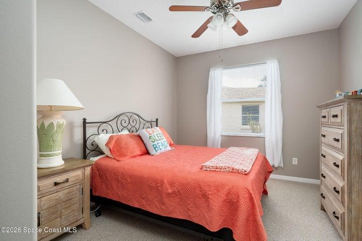 Vaulted ceiling bedroom featuring neutral wall tones, a ceiling fan with integrated lighting, window with white drapery and carpet flooring