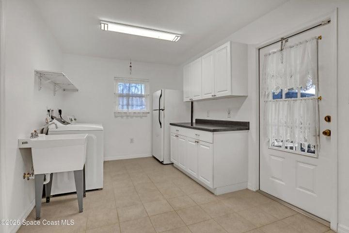 Bright laundry room with a window and door to pool deck, garage and family room.