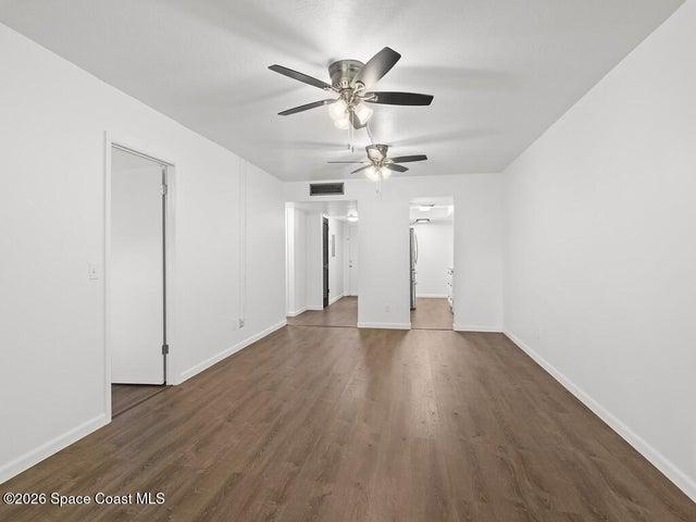 Open concept living area featuring wood-finish flooring, white baseboards, and a neutral wall palette