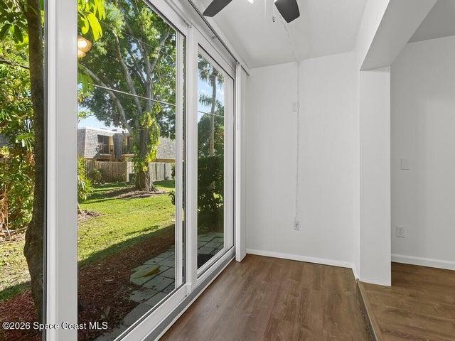 Sliding glass doors opening to a private backyard with mature trees