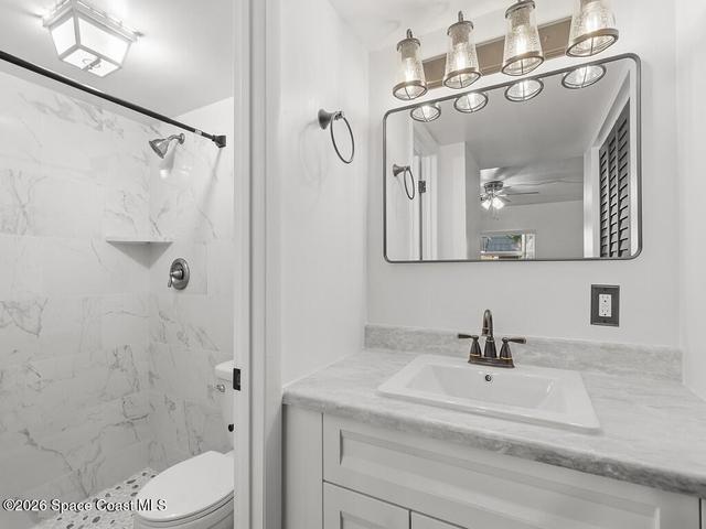 Bathroom featuring a vanity with an undermount sink, a stone-finish countertop, and a four-light fixture