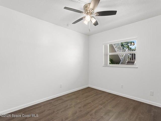 Room featuring wood-finish flooring, white baseboards, and a window with white trim