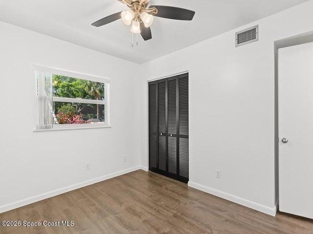 Bedroom featuring wood-finish flooring, a ceiling fan with integrated lighting, and a window with blinds