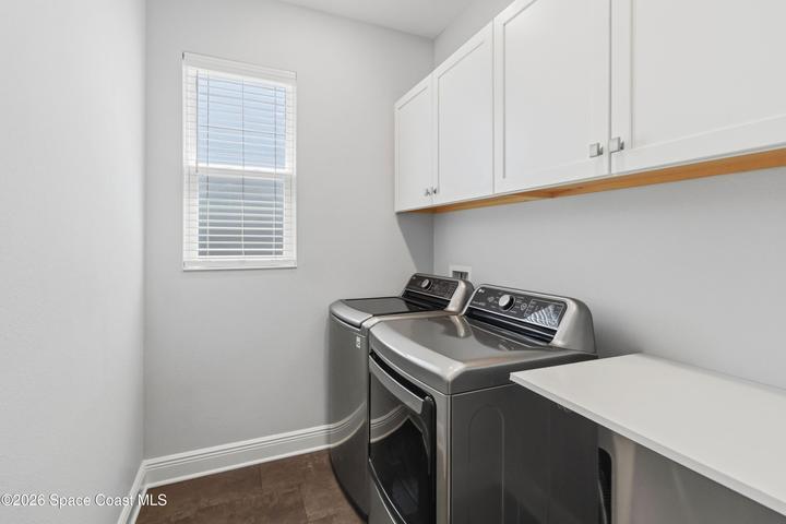 Laundry room with washer/dryer, folding table, and cabinets to store laundry products