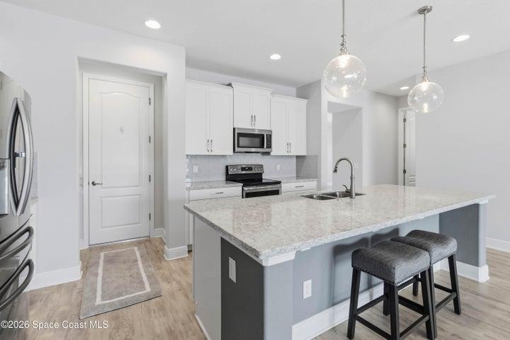 Stylist pendant lights and quartz countertops enhances the kitchen