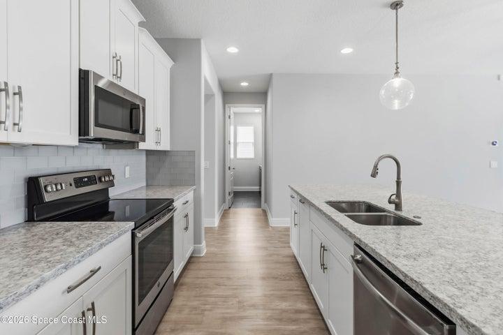 Stainless steel appliances, glass backsplash and quartz countertops
