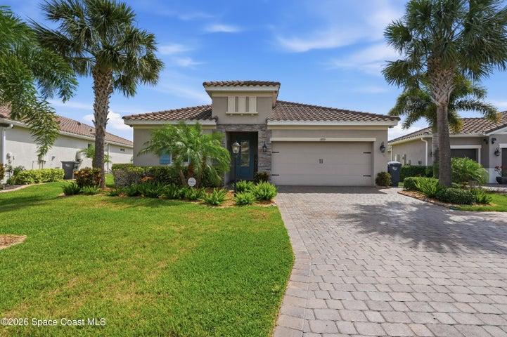 Paver driveway leading to a spacious garage and welcoming entryway