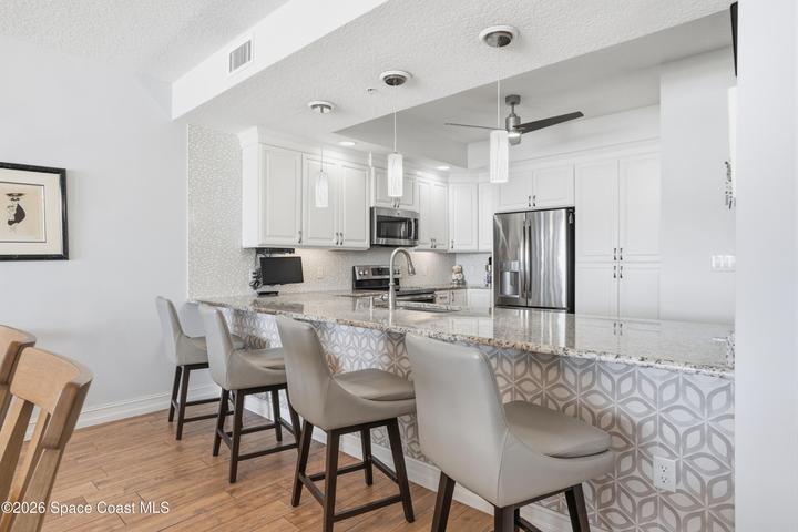 Custom tile along breakfast bar. Pendant lighting.