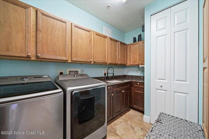 Laundry room with additional storage cabinetry, washer, dryer and dedicated laundry sink.