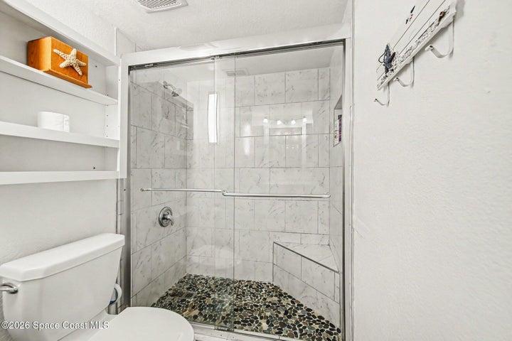 shower with toilet closed off from vanity
