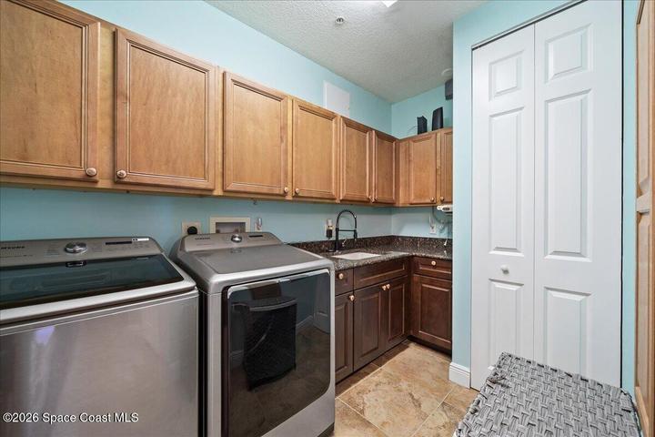 Laundry Room provides additional storage cabinetry and washer, dryer and in unit laundry sink.