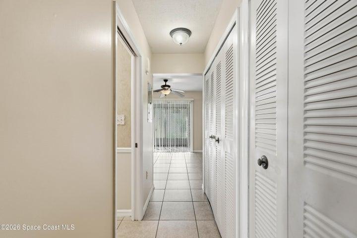Hallway leading to Kitchen, storage and laundry on one side and half bath on the other.