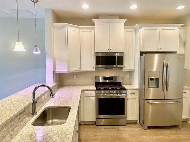STAINLESS STEEL APPLIANCES AND QUARTZ COUNTERTOPS IN WELL APPOINTED KITCHEN