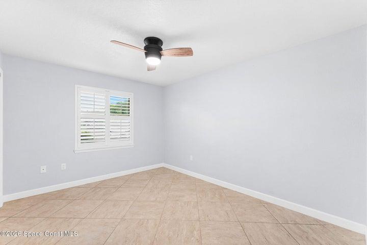 Guest bedroom with tile flooring, ceiling fan and plantation shutters
