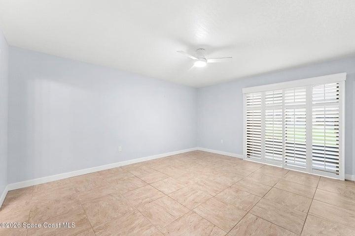 Primary bedroom with sliding door and plantation shutters out to the screened patio