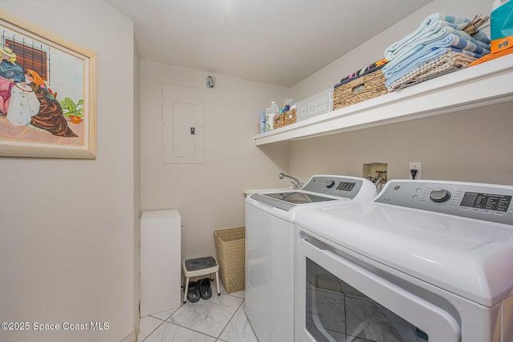 Spacious Laundry room with Utility Sink, Storage Cabinets, & GE Washer & Dryer.