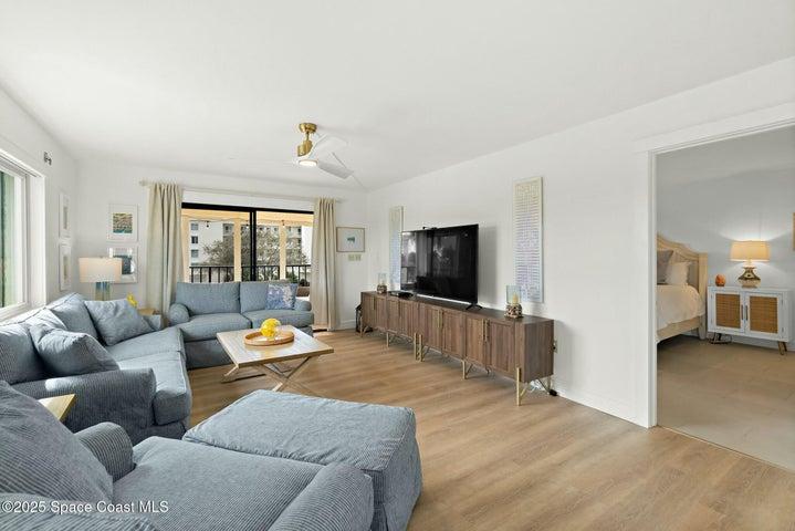 Living room with wood-look flooring and view toward primary bedroom, Riverwest condo, Cocoa Beach