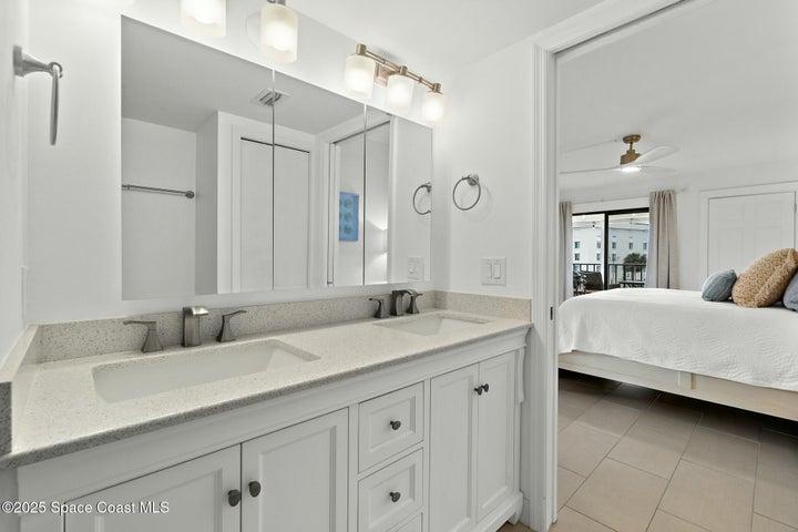 Primary bathroom dual vanity with quartz countertop and view into bedroom, Riverwest condo