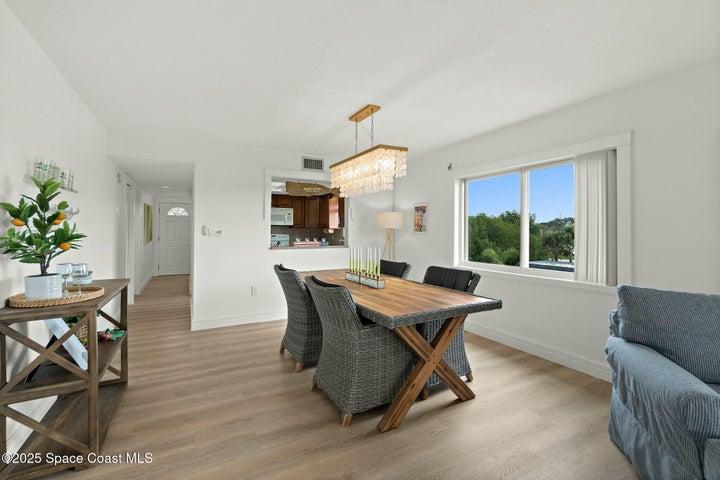 Open-concept dining area with wood-look flooring and pendant chandelier, Riverwest condo, Cocoa Beach