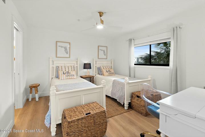 Guest bedroom with twin beds, ceiling fan, and window view of palm trees, Cocoa Beach condo