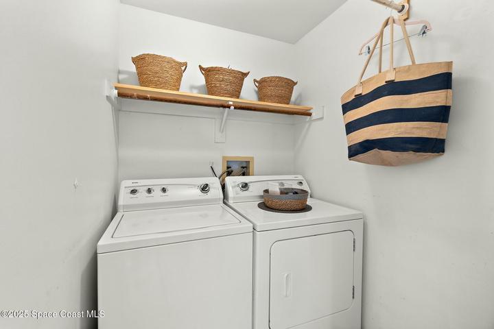 In-unit laundry closet with washer, dryer, and storage shelving, Riverwest condo, Cocoa Beach