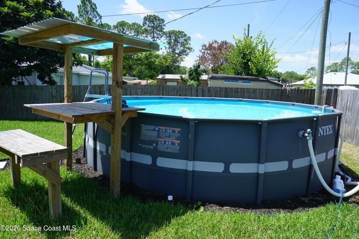 Backyard featuring an above-ground pool complete with a covered swim-up bar.