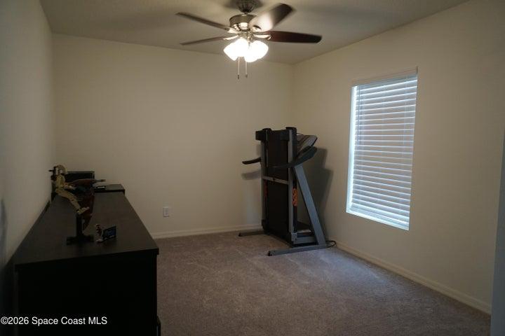 Office featuring a ceiling fan with light fixture, a window with horizontal blinds, and neutral wall tones
