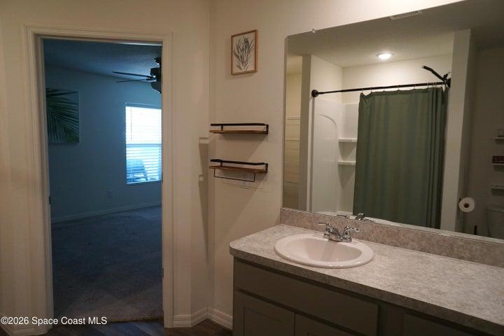 Primary Bathroom vanity with an integrated sink, polished chrome faucet, and a large wall-mounted mirror