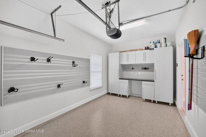 Garage w/epoxy flooring, workbench, storage cabinets and organized wall storage.