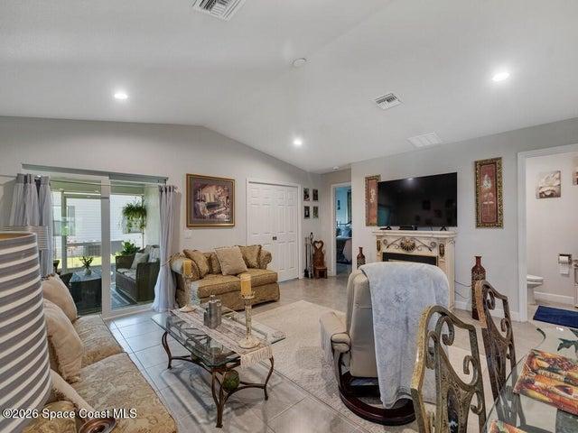 Living area featuring tile flooring, vaulted ceiling, recessed lighting, and sliding glass doors opening to an enclosed patio