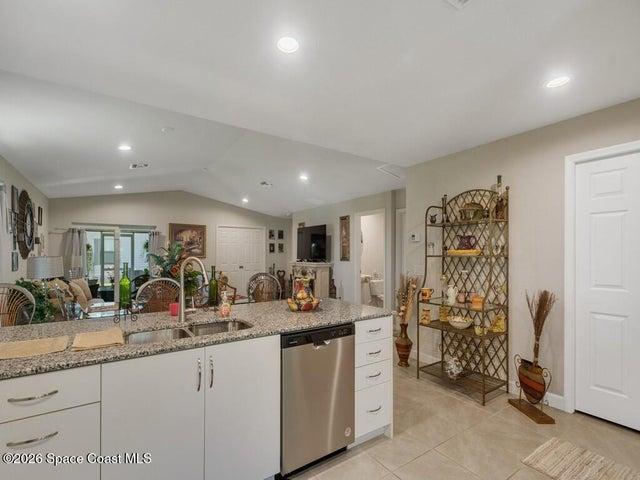 Kitchen island featuring a double basin stainless steel sink, a stainless steel dishwasher, and a light-toned granite countertop