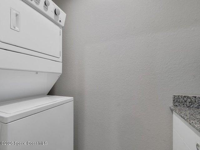 White stackable laundry appliances with a speckled countertop