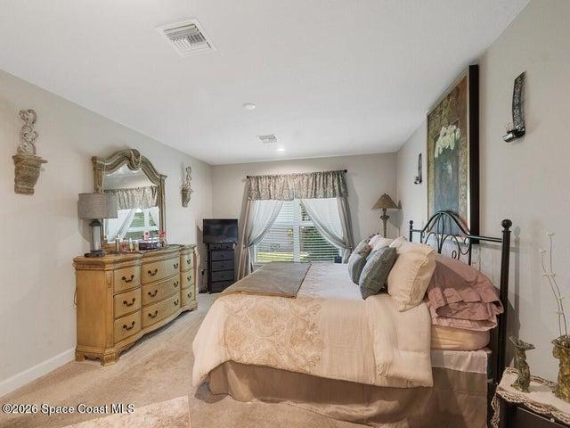 Spacious room featuring neutral carpeting, light-toned walls, and a large window with blinds and drapes