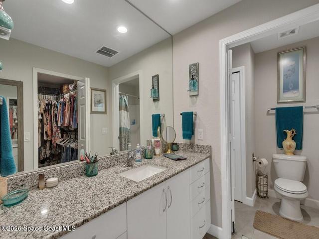 Bathroom featuring a spacious vanity with a granite countertop, undermount sink, and extensive mirror