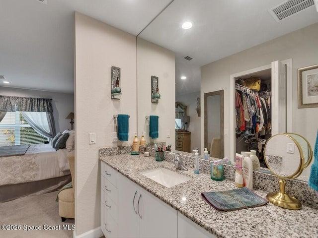 Bathroom vanity featuring a single integrated sink, granite countertop, and full-wall mirror