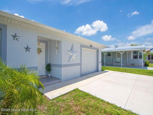 Modern single-story home featuring a white exterior with gray trim, a white metal roof, and an attached garage with a white door